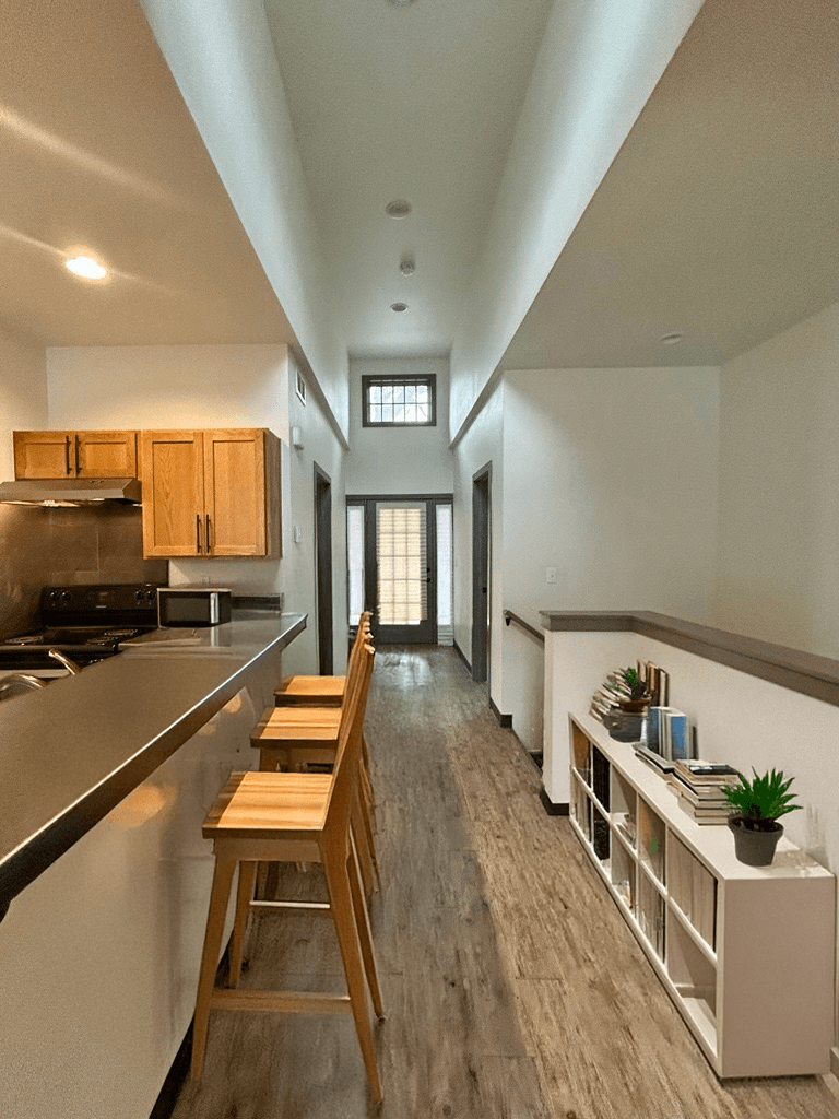 A long, narrow kitchen with wooden stools and a counter.